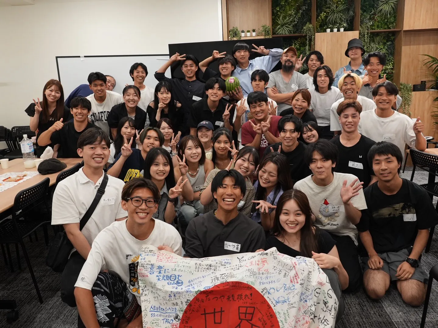 大人数が​集まり​盛り​上がる​報告会の​集合写真