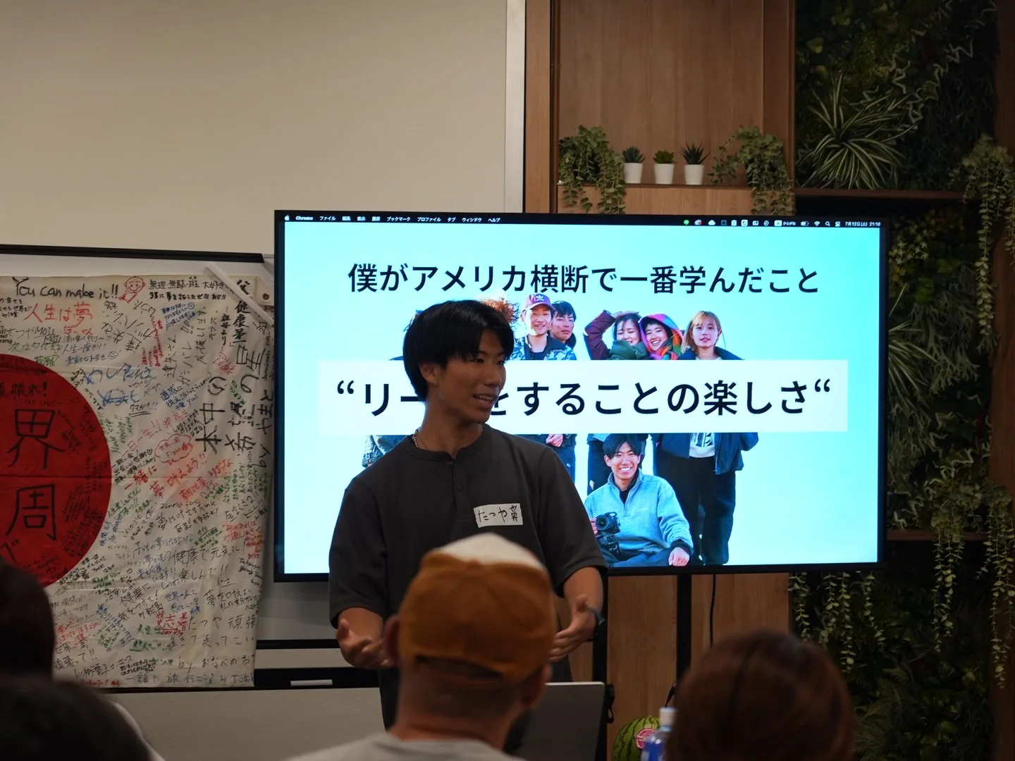アメリカ横断の​経験を、​スクリーンの​写真を​見せながら​語る​登壇者